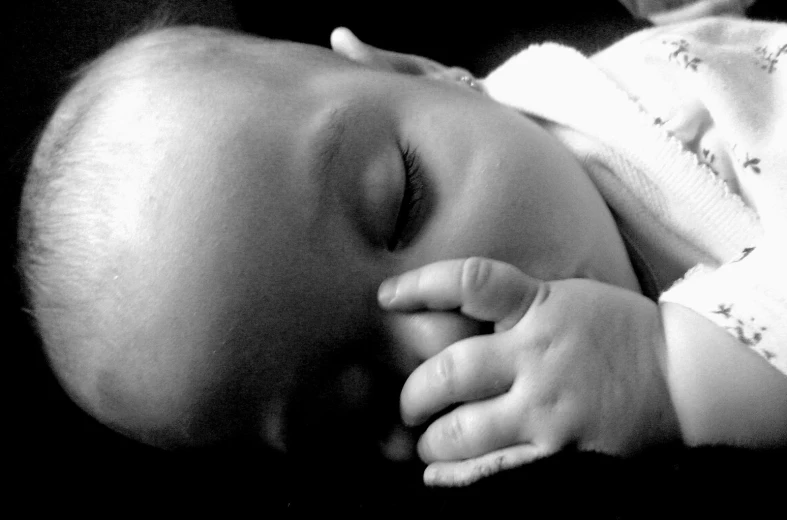 the head of a sleeping baby with its hands around a sleeping baby