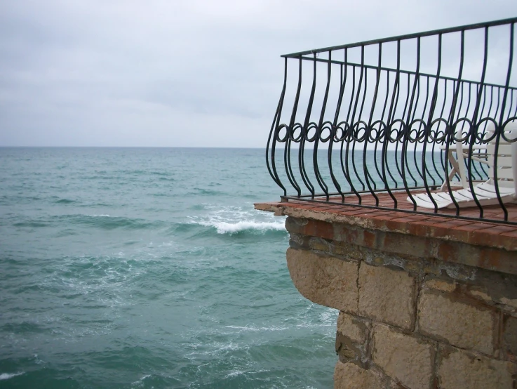 an iron balcony overlooking the ocean as it runs by