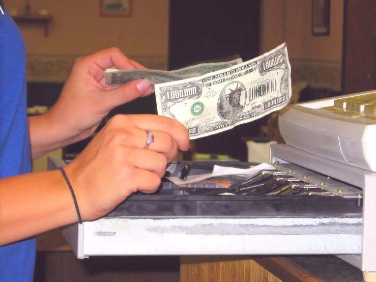 a hand holding a rolled dollar over an open safe