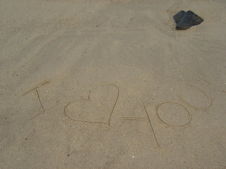 love written in the sand with a rock on the other side