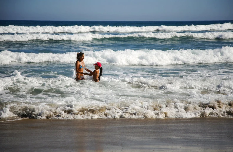 a woman and child play in the water at a beach