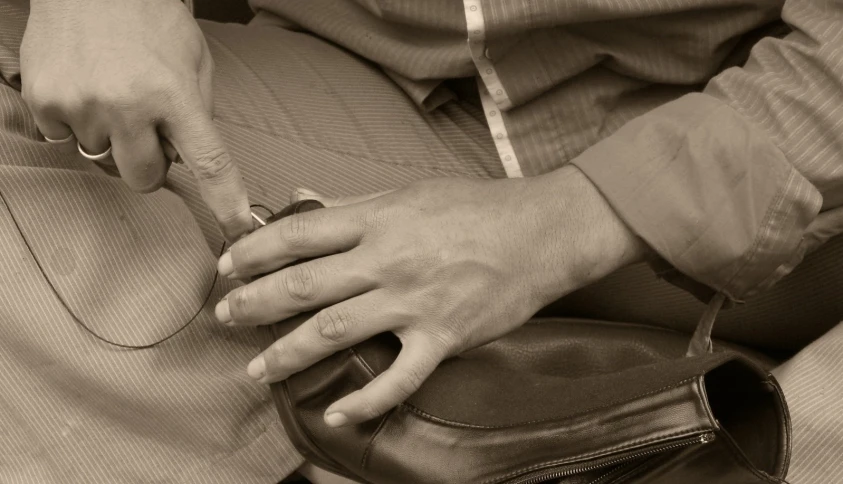 a man wearing dress pants is opening a purse