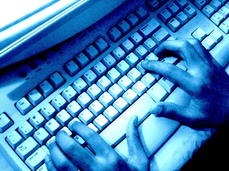 hands with fingers typing on a keyboard against a blue background