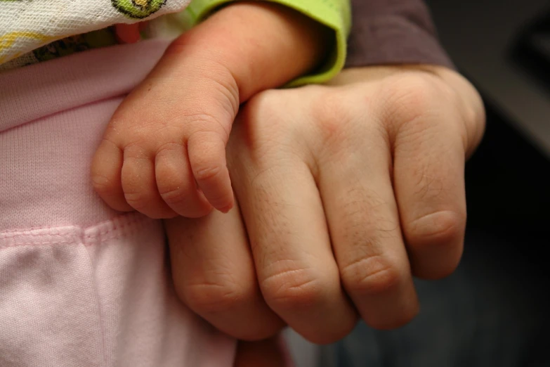 a baby being held in the arms of an adult