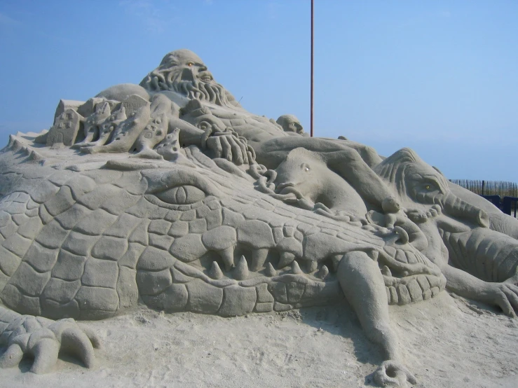 sand sculptures of animals on the beach, with sky in background