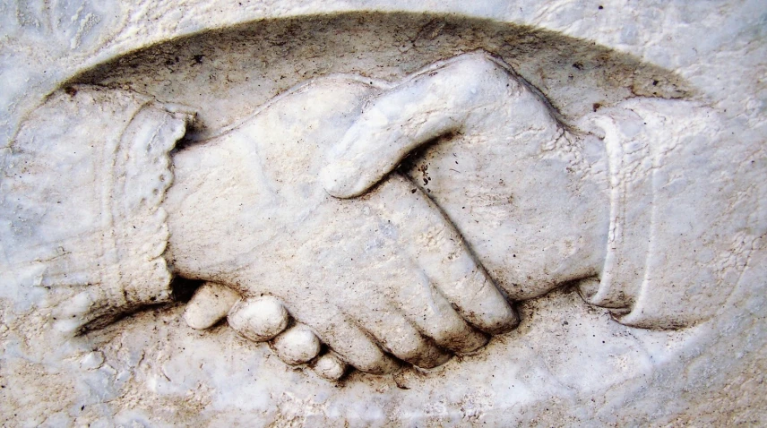 a couple of people shaking hands over sand