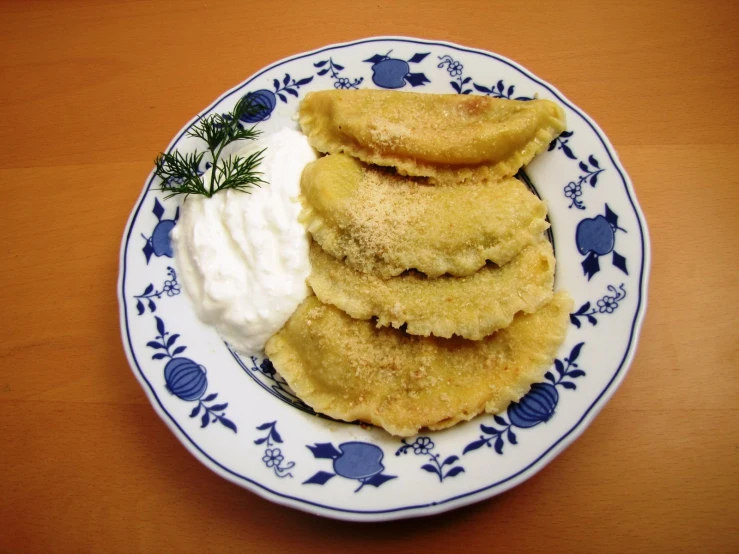 a white and blue plate holding pancakes with cream