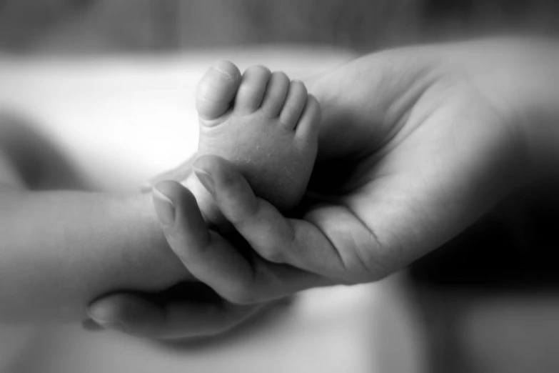 a hand holding a baby's foot with its hands