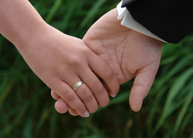 two people holding hands with wedding rings on each hand