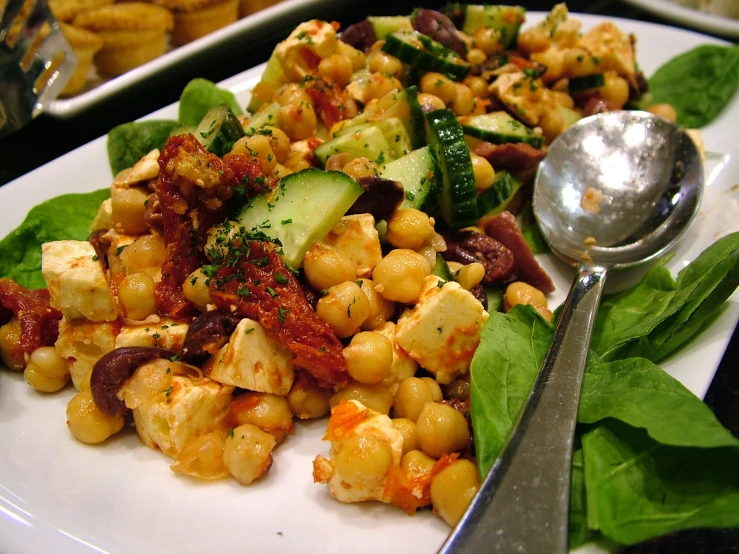 a plate filled with corn, cucumbers, and other food