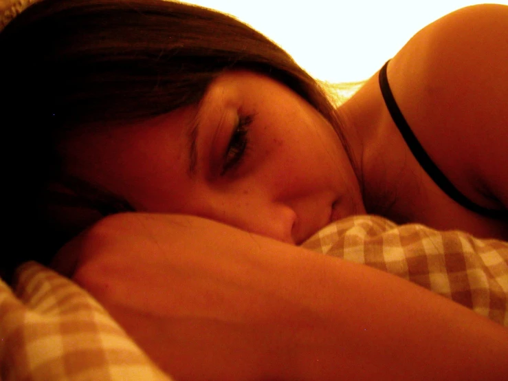 a woman laying down in bed with her eyes closed