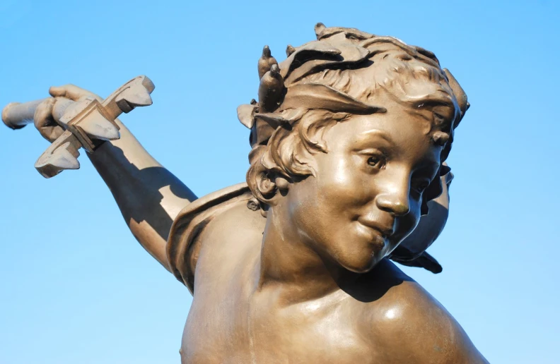 a bronze statue of a boy holding an airplane in his right hand