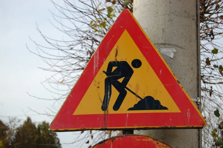 a warning sign with a person digging in the dirt