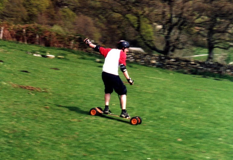 a person rides a skateboard on a grassy hill