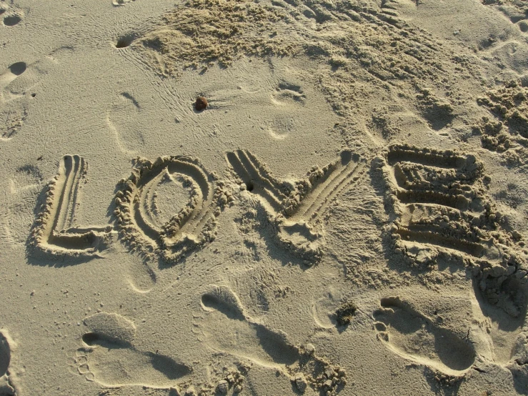 a word love written in sand with footprints