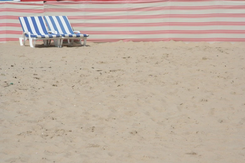 the beach chairs are in the sand beside a covering