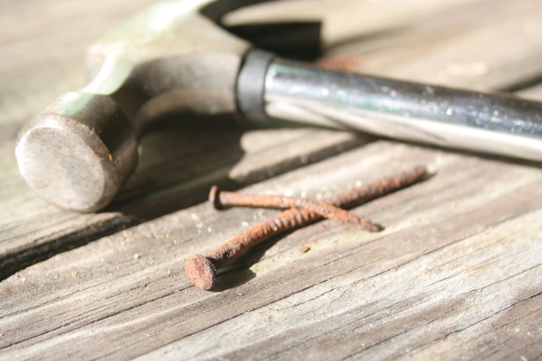 a hammer and three screws sitting on top of wood