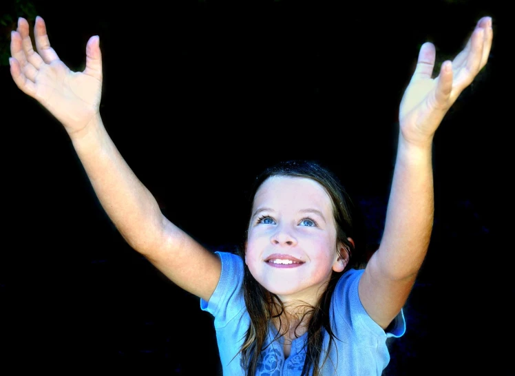 a girl is standing and smiling with hands in the air