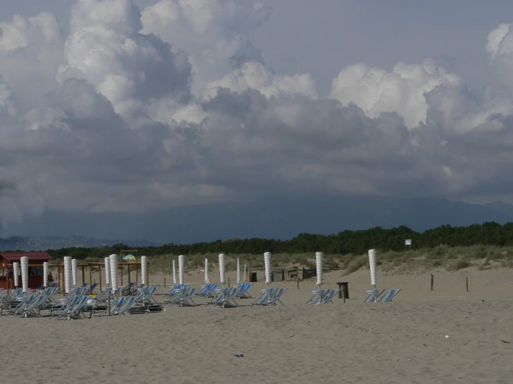 an empty beach covered in lawn chairs next to umbrellas