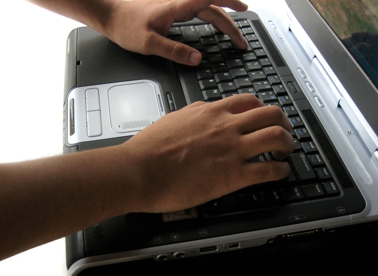 a pair of hands work on a laptop keyboard