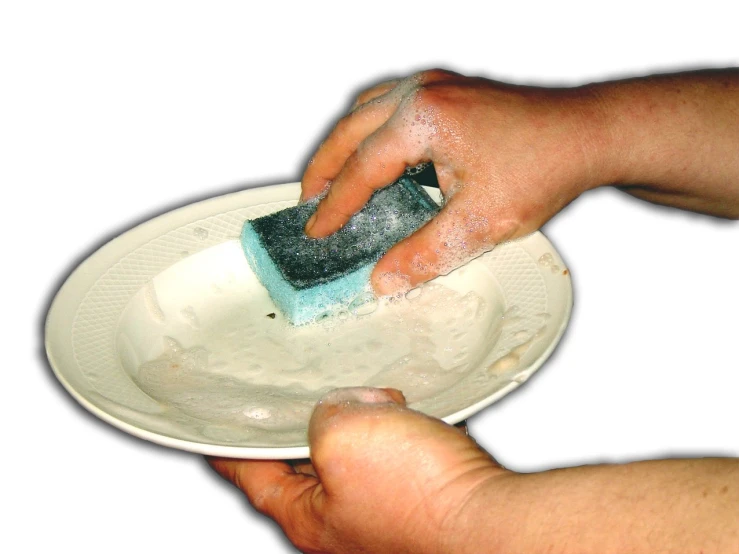 the hands are using a spatula to clean a plate