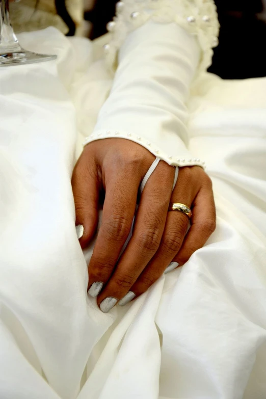 a person is wearing a wedding ring while sitting on a bed