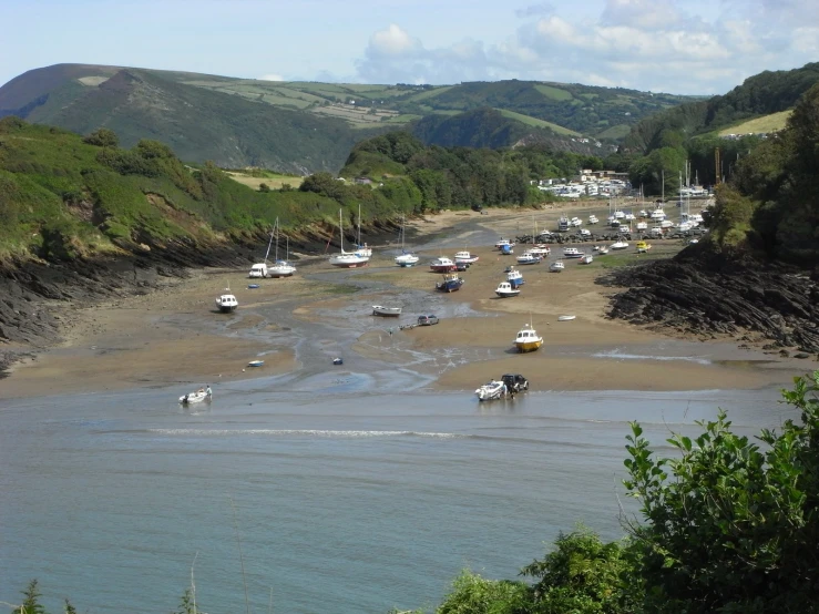 boats in the water on the shore of a beach