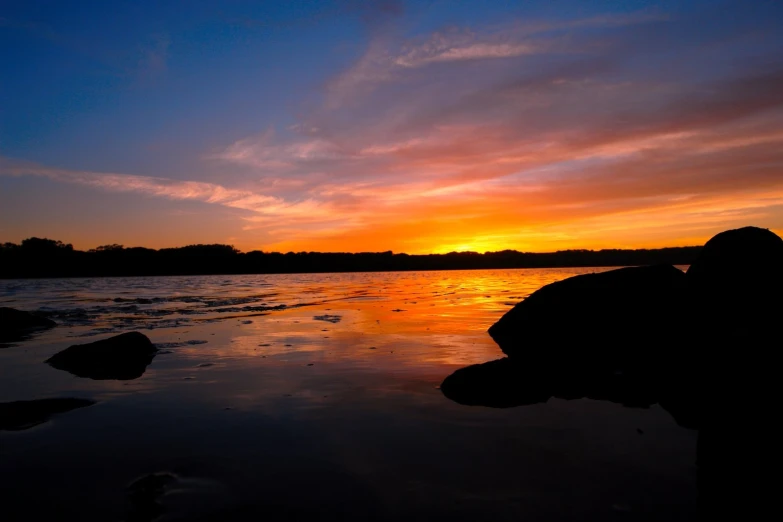 the sun sets over a body of water