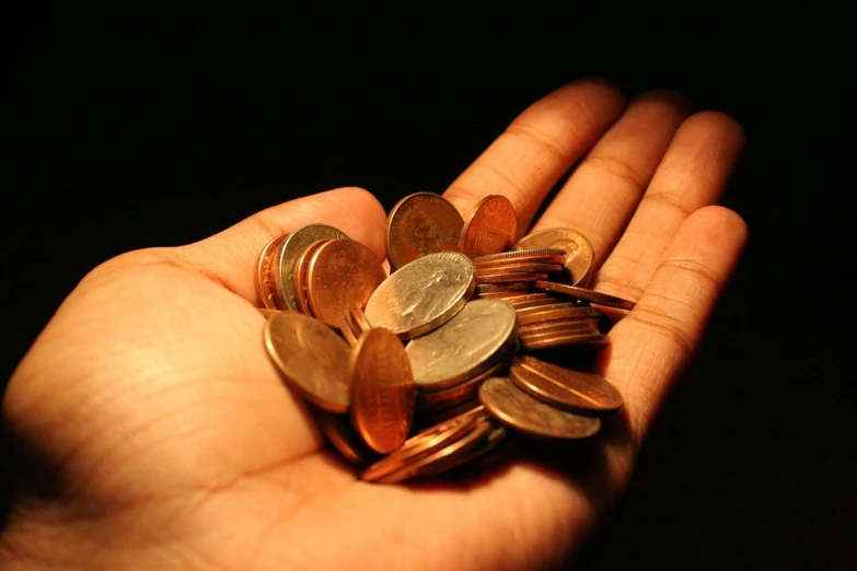 a person holding out their hand filled with coin coins