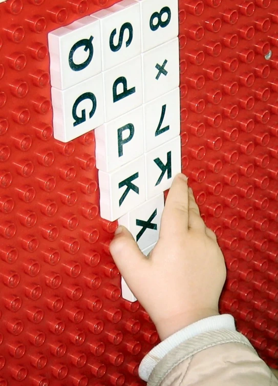 a person holding up a set of alphabet blocks