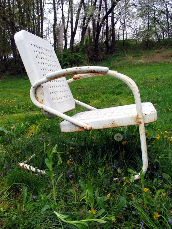 old chair left out in the grass in front of trees
