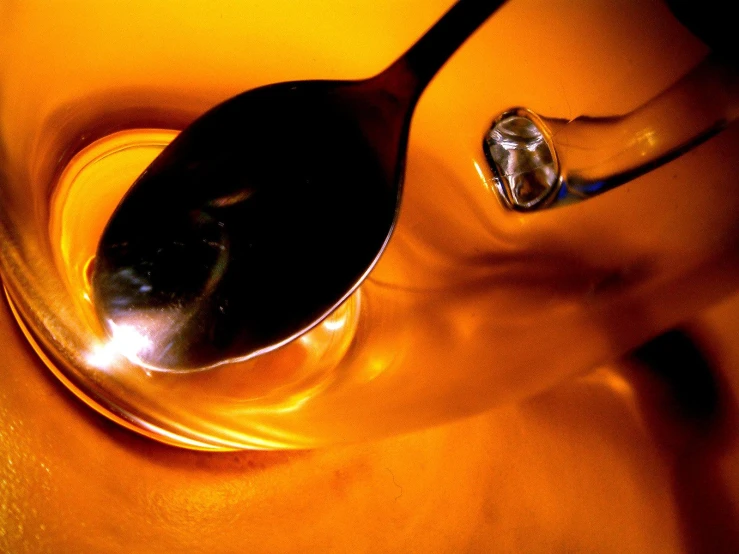 a spoon laying upside down next to the side of a yellow bowl