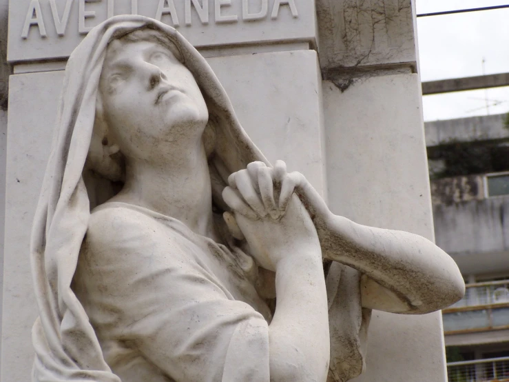 a statue of the praying mary outside a building