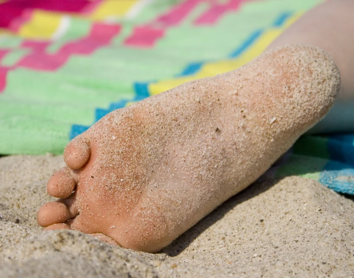 a close up of a person's foot on the beach