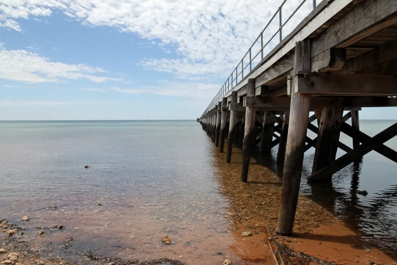 water beneath the pier under a partly cloudy sky