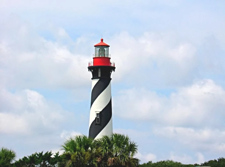 a tall lighthouse with a red top in the water