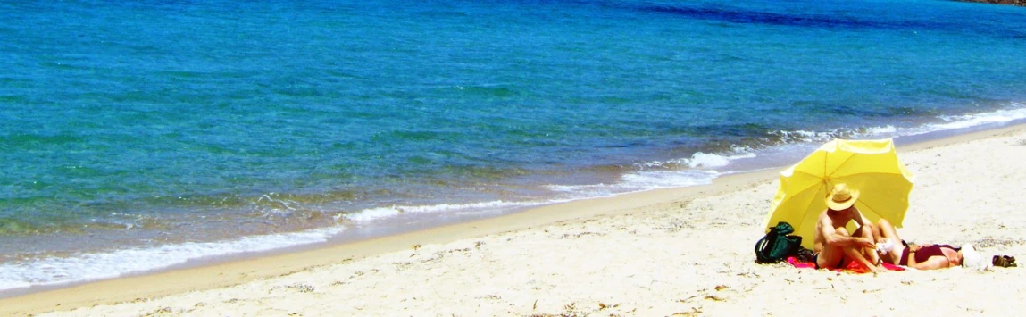 there are two people under an umbrella on the beach