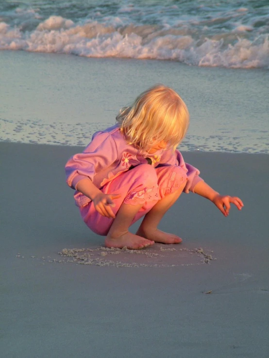 a toddler plays in the sand at the beach