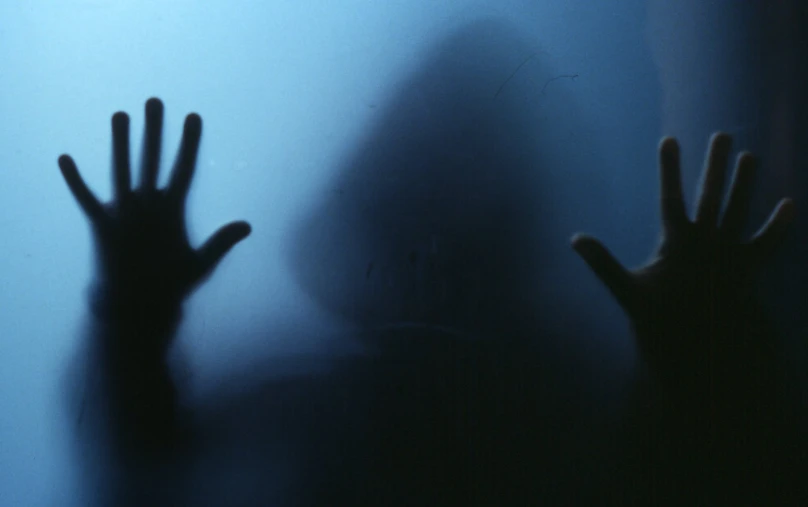 silhouette of person and hand behind frosted glass