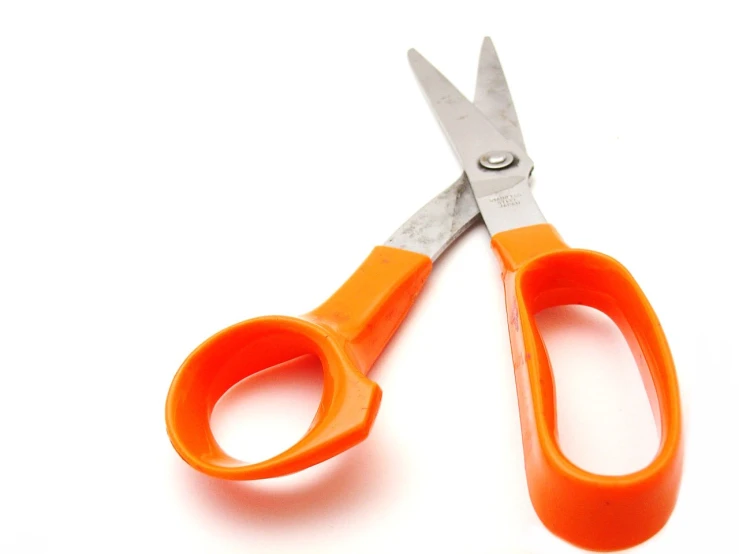 two pairs of orange handled scissors on white background