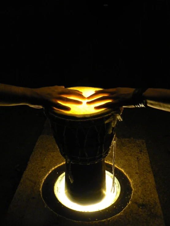 a drum being held by two hands while sitting on the ground