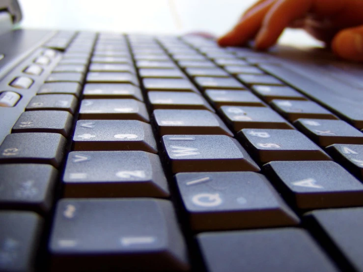 someone typing on a laptop keyboard with their hand