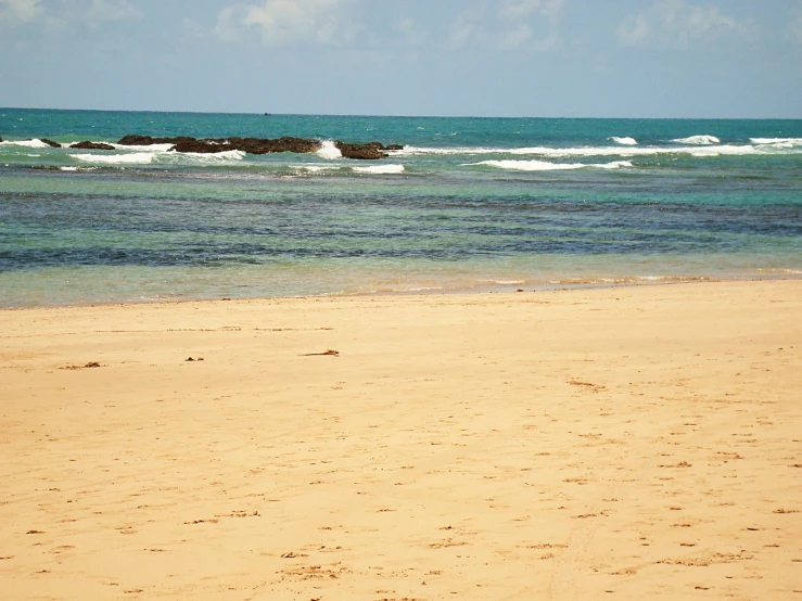 a woman standing on the beach with her surfboard