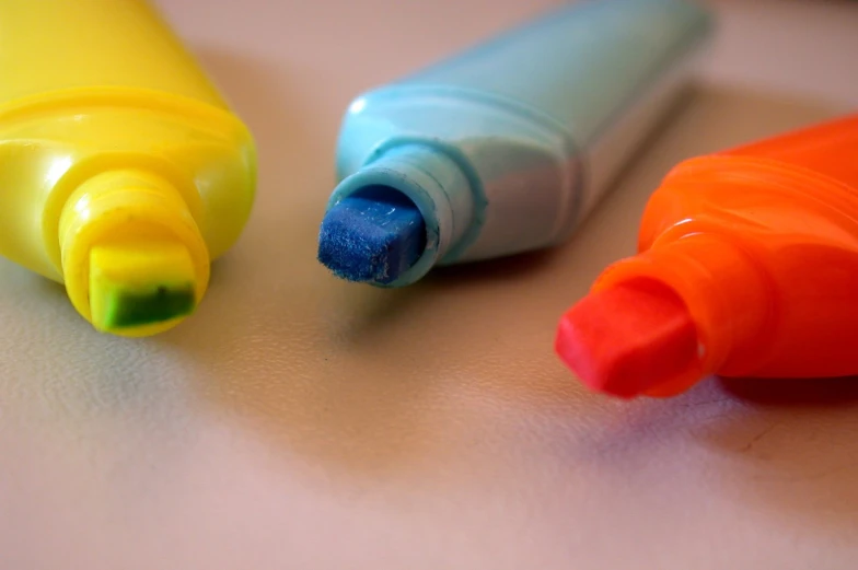 three crayons on a surface with one has blue and one has orange