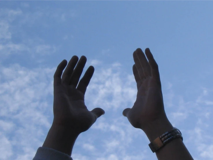 two hands raised up for the sky to reach for soing