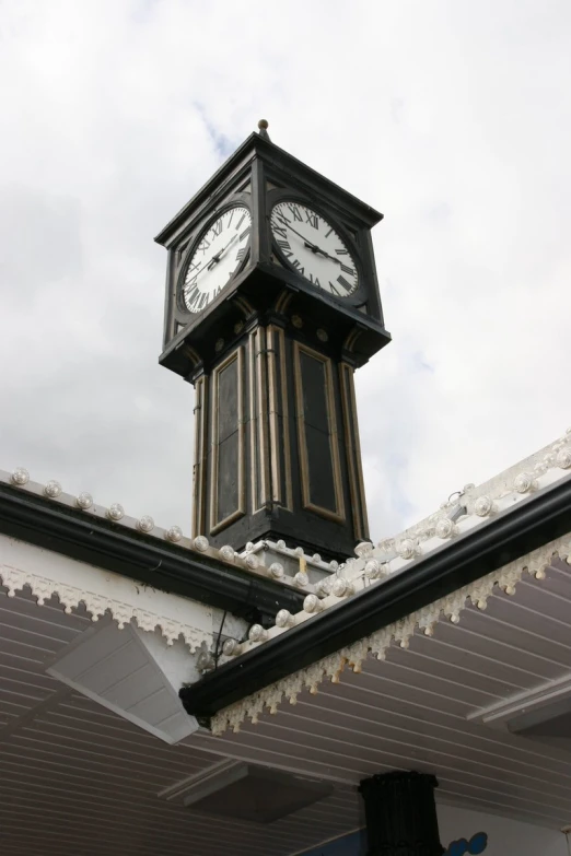 a tall clock tower above a roof under a cloudy sky