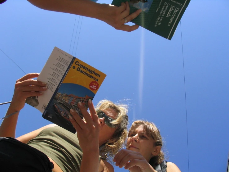 there are many people that are outside and one is holding a book