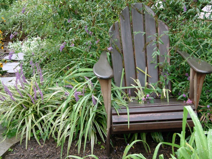 the view of a rocking chair sitting next to flowers