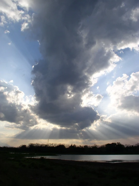 clouds gather over a pond as the sun shines through