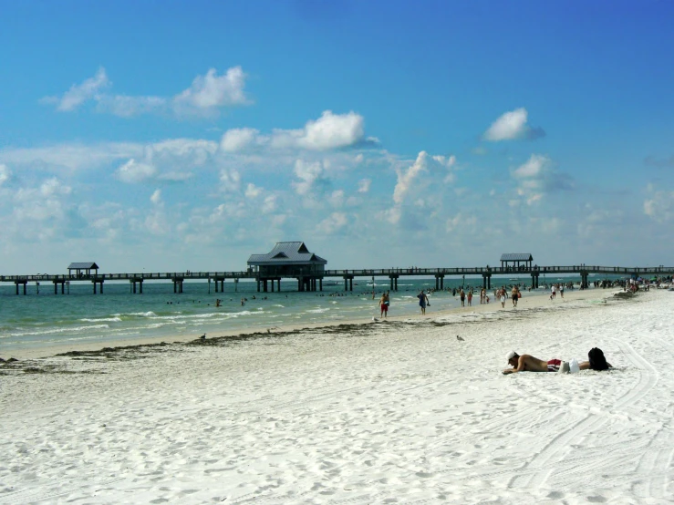 people on the beach and in the water with pier